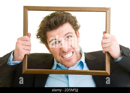 Junger Mann im Anzug schaut durch ein leeres Holz Rahmen Stockfoto