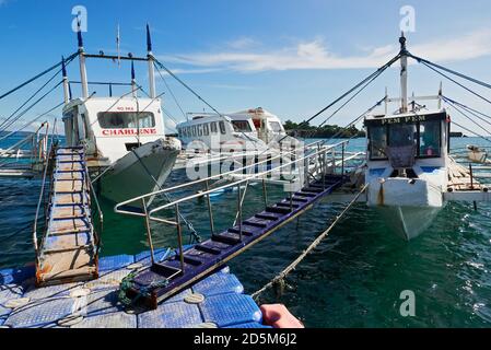 Traditionelle Fährschiffe dockten an einer schwimmenden Kunststoffplattform im Hafen Tabon in Caticlan, Provinz Aklan, dem Tor zur Insel Boracay, Philippinen Stockfoto