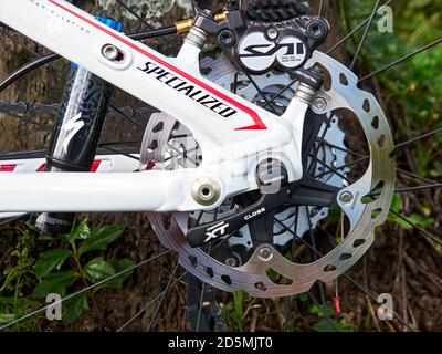 Nahaufnahme eines speziellen Epic Mountainbike-Rahmens mit einem Shimano Saint Hinterrad-Scheibenbremsen-Rotor aus glänzendem Metall, mit natürlichem Hintergrund Stockfoto