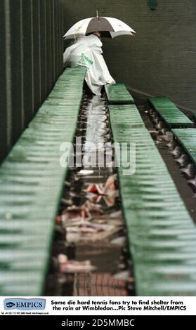 Einige sterben hart Tennis-Fans versuchen, Schutz vor zu finden Der Regen in Wimbledon Stockfoto