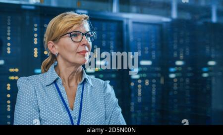 Porträt einer schönen leitenden IT-Technikerin im modernen Rechenzentrum. Im Hintergrund funktionierende Server-Racks mit blinkenden LED-Anzeigen. Stockfoto