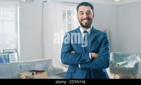 Erfolgreicher Immobilienmakler in einem Anzug smiles und bietet Schlüssel aus einer neuen Wohnung. Stehen in der Mitte des Raumes, der renoviert wird. Geräumig Neu Stockfoto