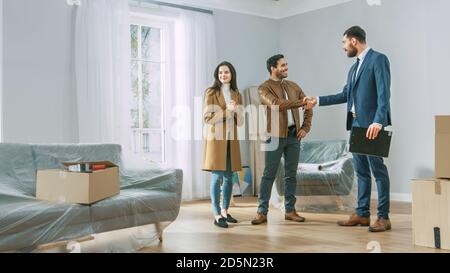 Professional Real Estate Agent zeigt helle neue Wohnung zu jungen Paar. Erfolgreiches junges Paar immer Hausbesitzer, Siegel der Deal mit Immobilien Stockfoto