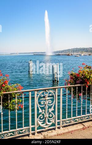 Der Jet d'Eau Wasserstrahlbrunnen in der Bucht von Genf, Schweiz, mit einem schmiedeeisernen Geländer mit Anker und Topfblumen an einem sonnigen Sommertag. Stockfoto