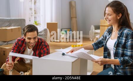 Happy couple Montage von Möbeln als Team, Mädchen liest Anweisungen und Junge zieht Schraube mit einem Bohrer. Umzug in neue Wohnung, paar montieren Stockfoto