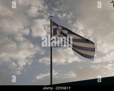 Wehende, griechische Flagge vor dem Himmel am Mittelmeer. Griechische Flagge winkt vor dem mediterranen Himmel. Stockfoto