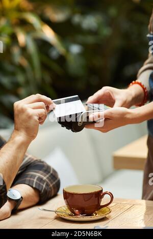 Nahaufnahme des Mannes, der für eine Kaffeetasse mit Kreditkarte bezahlt An den Kellner im Restaurant Stockfoto