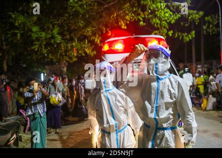 Mandalay, Myanmar. September 2020. Gesundheitshelfer, die persönliche Schutzanzüge (PSA) tragen, werden gesehen, wie sie draußen neben den Krankenwagen auf die vermuteten Covid-19-Patienten warten.EIN Mann aus dem Viertel der Gemeinde Amarapura testete positiv auf Coronavirus (COVID19), obwohl er keine Covid-19-Zeichen gezeigt hatte. Es gibt mehr als 25 Menschen, die in engem Kontakt mit ihm gewesen sind, also sind medizinische Arbeiter mit Krankenwagen in das Viertel geeilt, um zu sehen, dass die Menschen, die in engem Kontakt mit dem Covid-19 Opfer waren, zur näheren Untersuchung in die Quarantänestelle gebracht werden. (Bild: Stockfoto