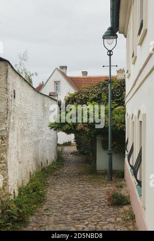 Malerische gepflasterte Straße in Střešovičky, auch bekannt als Malé Střešovice (kleine Střešovice) in Prag, Tschechische Republik. Střešovičky ist eine ehemalige Arbeitersiedlung mit kleinen Häusern aus dem Ende des 18. Jahrhunderts, die ihre ursprüngliche Atmosphäre im Laufe der Jahrhunderte unberührt erhalten hat und heute als romantischer Ort ohne Touristen in den Prager Außenbezirken bekannt ist. Na Kocourkách Lane ist auf dem Foto dargestellt. Stockfoto