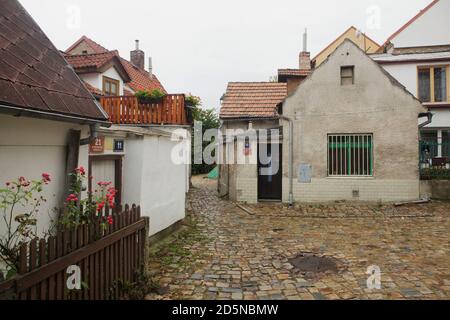 Malerische gepflasterte Straße in Střešovičky, auch bekannt als Malé Střešovice (kleine Střešovice) in Prag, Tschechische Republik. Střešovičky ist eine ehemalige Arbeitersiedlung mit kleinen Häusern aus dem Ende des 18. Jahrhunderts, die ihre ursprüngliche Atmosphäre im Laufe der Jahrhunderte unberührt erhalten hat und heute als romantischer Ort ohne Touristen in den Prager Außenbezirken bekannt ist. Na Kocourkách Lane ist auf dem Foto dargestellt. Stockfoto