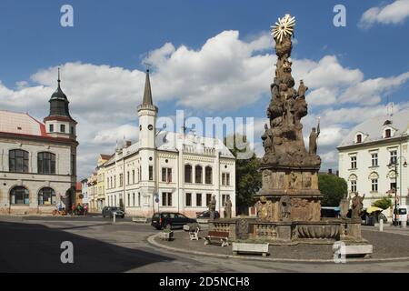 Die Säule der Heiligen Dreifaltigkeit (Sloup Nejsvětější Trojice) wurde vom böhmischen Bildhauer Ondřej Dudke (1708) auf dem Hauptplatz in Zákupy in Nordböhmen, Tschechische Republik, entworfen. Im Hintergrund ist das neugotische Gebäude des Rathauses (1867) zu sehen. Stockfoto