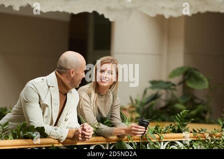 Lächelnde junge Frau, die mit dem Mann spricht, während sie stehen Auf dem Balkon Stockfoto