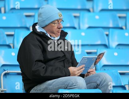 Ein Manchester-City-Fan auf den Tribünen liest ein Match vor Tagesprogramm vor dem Start Stockfoto