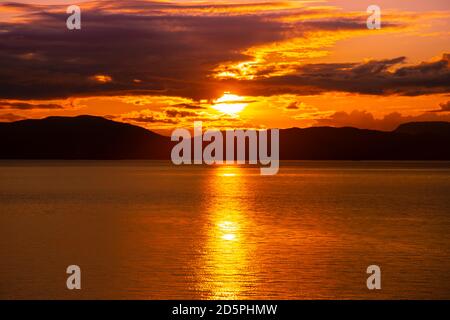 Sonnenuntergang über dem Meerwasser mit der Alaskan Küste in Silhouette Stockfoto