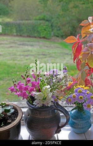 Bunte bunte Bouquet von hausgemachten geschnitten Garten Blumen in Krug, Topf und Vase auf einer Wohnküche Fensterbank im Herbst UK Großbritannien KATHY DEWITT Stockfoto