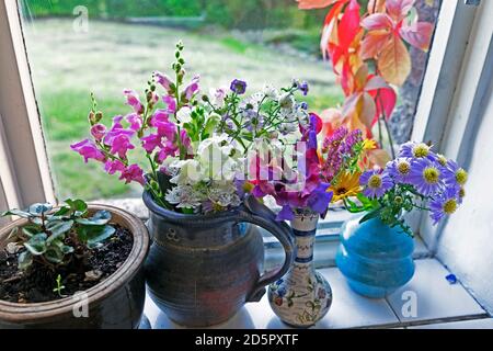 Bunte bunte Bouquet von hausgemachten geschnitten Garten Blumen in Krug, Topf und Vase auf einer Wohnküche Fensterbank im Herbst UK Großbritannien KATHY DEWITT Stockfoto