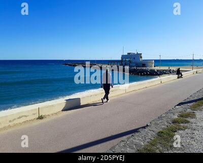 Ein Mann, der in Strandnähe auf einer Promenade läuft. Platja de la Nova Mar Bella. Passeig Marítim del Bogatell, Barcelona, Katalonien, Spanien. Stockfoto