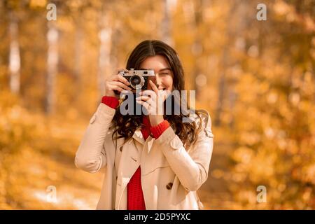 Porträt von glücklichen weiblichen Fotografen mit Retro-Kamera fotografieren Von schönen Herbst im Park Stockfoto