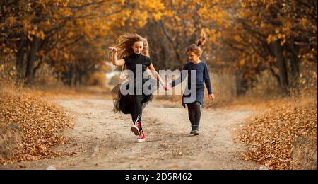 Zwei Mädchen im Teenageralter gehen im warmen Herbst an einer Waldstraße entlang. Stockfoto