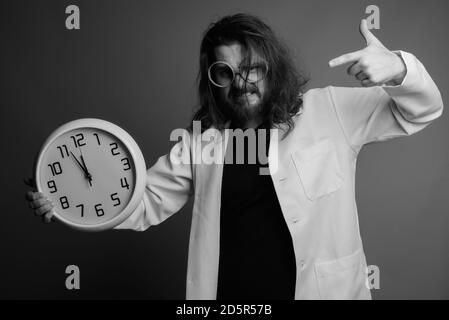 Junger bärtiger Mann Arzt gegen grauer Hintergrund Stockfoto