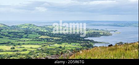 Grüne Felder und ländliche Landschaft mit Blick auf Lough Derg in Ballycuggarran, County Clare, Irland Stockfoto
