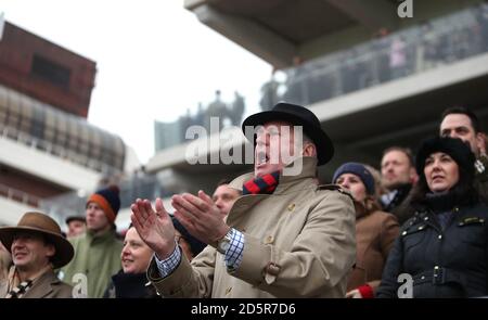 Racegoers sehen sich die Action auf der Cheltenham Racecourse an Stockfoto