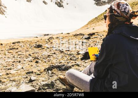 Frauen reisen alleine und genießen einen wunderbaren Tee und die Aussicht in die Berge, die auf dem Camping sitzen. Outdoor Reisen Abenteuer Lifestyle Konzept Wandern Wanderl Stockfoto