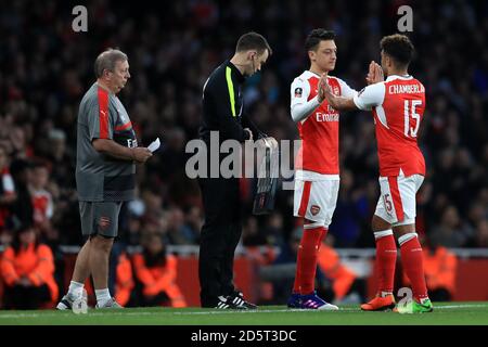 Arsenals Alex Oxlade-Chamberlain (rechts) wird durch Arsenals Mesut Ozil ersetzt In der ersten Hälfte Stockfoto