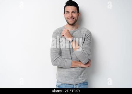 Hübscher junger Mann auf weißem Hintergrund, der die Kamera anschaut. Fröhlicher Typ, der lächelt Stockfoto