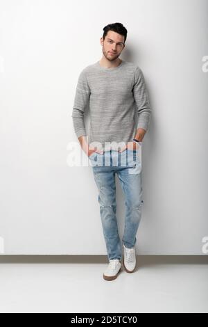 Volle Länge der schönen jungen Mann auf weißem Hintergrund Blick auf die Kamera. Fröhlicher Typ, der lächelt Stockfoto