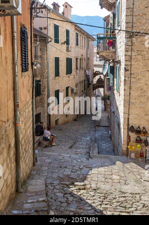 Zwei Touristen, die sich in einer engen gepflasterten Straße in Kotor, Montenegro, ausruhen Stockfoto