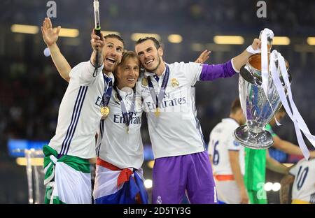 Sergio Ramos von Real Madrid (links), Luka Modric (Mitte) und Gareth Bale feiern mit der Trophäe nach dem Champions-League-Finale 2017 im Nationalstadion von Cardiff Stockfoto