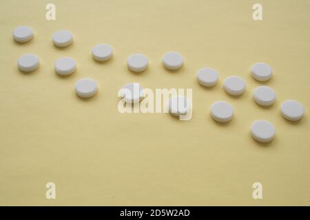 Runde weiße Farbtabletten auf einem gelben Hintergrund sind Tabletten in einer Reihe im Bild angeordnet Stockfoto