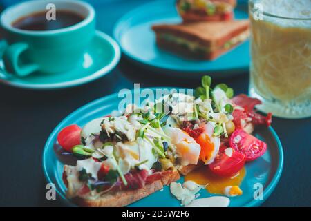 Buntes gesundes Sandwich mit Eiern, Spanish-Jamon-Fleisch in Scheiben geschnitten, getrocknete Tomaten Serviert auf Bruschetta Brotlaib zum Mittagessen.Genießen Sie leckere Mediterranea Stockfoto