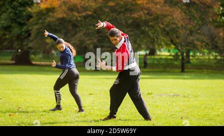 London, Großbritannien. 14. Oktober 2020. UK Wetter: Ein Paar übt Tai Chi, auch Tai Chi chuan genannt, als die Blätter auf Bäumen im Green Park beginnen, ihre Herbstfarbe zu nehmen. Ursprünglich als Kampfkunst im China des 13. Jahrhunderts entwickelt, wird Tai Chi heute weltweit als gesundheitsfördernde Übung praktiziert und verbindet tiefes Atmen und Entspannung mit fließenden Bewegungen. Gute Sonneneinbrüche im Frühjahr und Sommer, gefolgt von Regenfällen im September, lassen den diesjährigen Herbstlaub in diesem Jahr besonders eindrucksvoll erscheinen. Kredit: Stephen Chung / Alamy Live Nachrichten Stockfoto