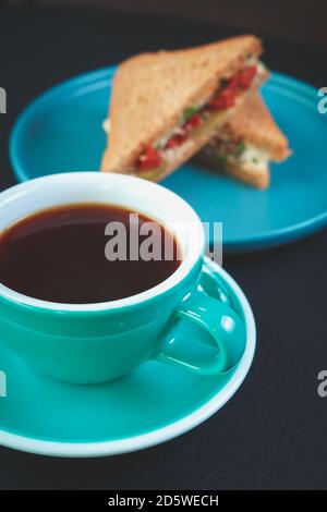 Tasse frischen schwarzen Kaffee serviert auf dem Tisch im Café Mit Club Sandwiches im Hintergrund.Genießen Sie heiße energetische Getränke zum Mittagessen Im italienischen Café.Traditiona Stockfoto