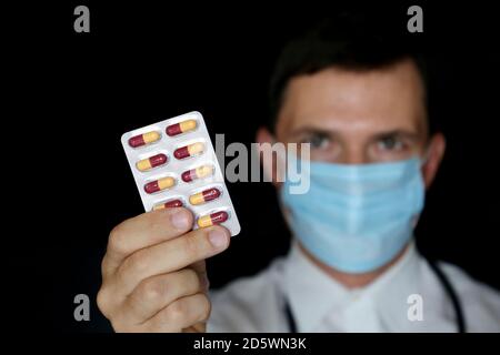 Arzt in medizinische Maske hält Blister Packung Pillen, männliche Hand mit Medikamenten aus der Nähe. Konzept von Apotheker, Medikamente, Antibiotika oder Vitamin Stockfoto