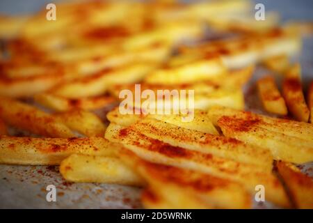 Pommes frites im Ofen mit geräuchertem Paprikapulver gebacken.Delicious Hausgemachte Kartoffelchips im Ofen auf Pergamentpapier gekocht.lecker natürlich Zubereitung von Speisen Stockfoto