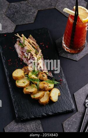 Hering mit neuen Kartoffeln auf schwarzem Hintergrund Stockfoto