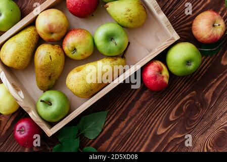 Äpfel und Birnen in einem Tablett auf einem hölzernen Hintergrund Stockfoto