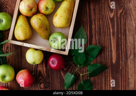 Äpfel und Birnen in einem Tablett auf einem hölzernen Hintergrund Stockfoto