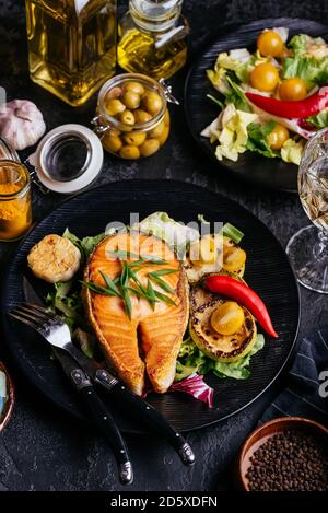Lachssteak auf Kohlen mit Gemüse auf einem schwarzen gebacken Hintergrund Stockfoto