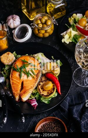 Lachssteak auf Kohlen mit Gemüse auf einem schwarzen gebacken Hintergrund Stockfoto