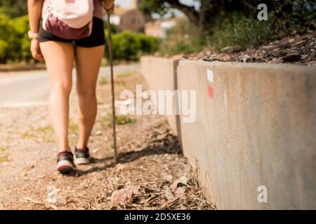 Signal für Trekkingperson, den richtigen Weg zu finden und dem richtigen Weg zu folgen. Bemaltes Schild an der Wand. Konzept des Wandertourismus. Junge Frau zu Fuß o Stockfoto