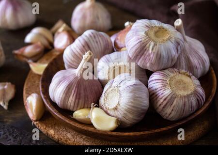Knoblauch Nahaufnahme. Knoblauchzehen und Glühbirne auf rustikalem Holztisch. Stockfoto