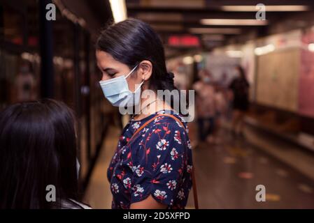 Junge Brünette Frau trägt Gesichtsmaske auf der U-Bahn-Station. Stockfoto