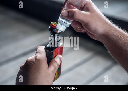Mann fllt elektronische Zigarette fr gesundes Rauchen ohne Nikotin.  Detail der Hnde, die Flssigkeit in die Maschine gieen Stockfotografie -  Alamy