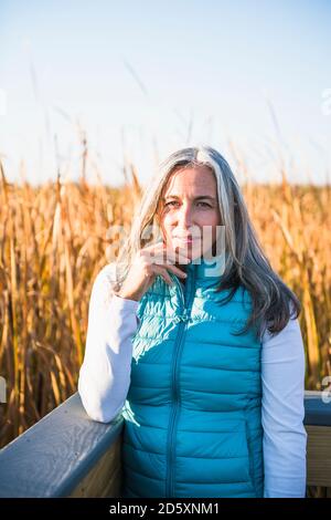 Grauhaarige Frau genießt einen Naturspaziergang in goldenem Sumpf Stockfoto