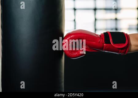 Konzept einer Seitenansicht eines roten Stanzhandschuhs Hand schlagen einen geraden Boxsack in einer Turnhalle Stockfoto