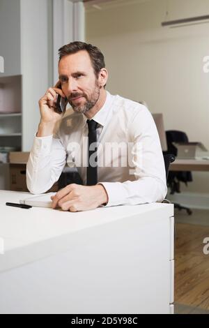 Geschäftsmann, der am Schreibtisch im Büro telefoniert Stockfoto